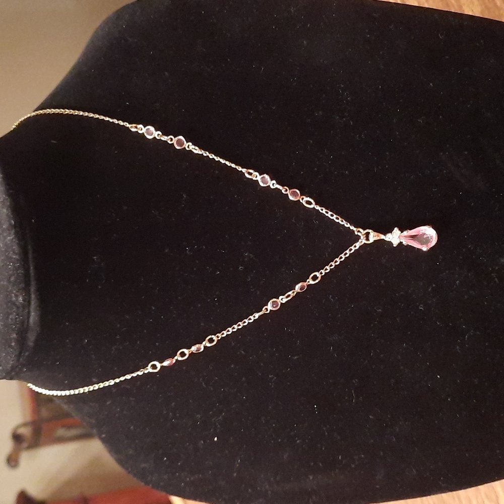 Avon necklace with large pink stone and smaller stones on gold tone chain.